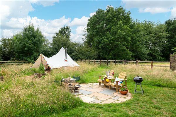 Bell tent in private enclosed paddock surrounded by woodland trees with fire pit patio 
